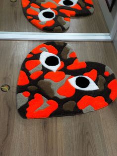 two rugs that have been made to look like hearts with eyes on them, one is orange and the other is black