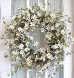 a wreath with daisies is hanging on the front door