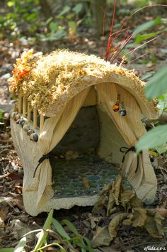 a stuffed animal house in the middle of some dirt and grass with leaves around it