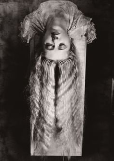 a black and white photo of a man with long hair wearing a mask on top of his head