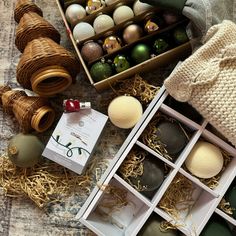 an assortment of christmas ornaments in boxes on a table with yarn and twine spools