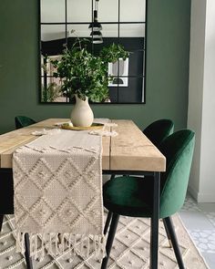 a dining room table with green chairs and a white vase on top of the table