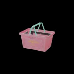 a pink plastic shopping basket with handles and straps on the handle, against a black background