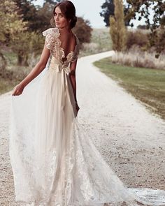 a woman in a white dress is walking down the road with her hand on her hip