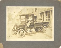 an old black and white photo of a man sitting in the driver's seat of a truck