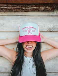 a woman with long black hair wearing a pink and white trucker hat that says happy up alaska day