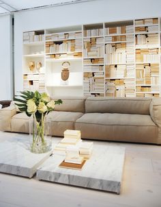 a living room filled with furniture and bookshelves next to a vase full of flowers