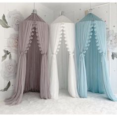 three different colored canopy beds with flowers on the wall