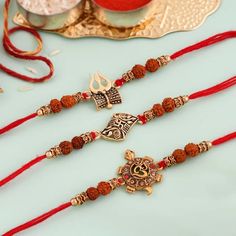 two red and gold necklaces sitting next to each other on a plate with a cup in the background