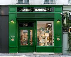 the storefront of grana do pharmacias is painted bright green and has plants in it