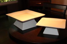 two square plates sitting on top of a wooden table next to each other in front of a window