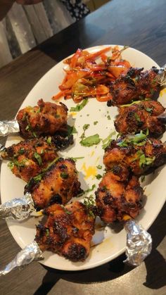 a white plate topped with lots of food on top of a wooden table covered in foil