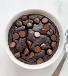 a chocolate cake in a white bowl on a table with a knife and fork next to it