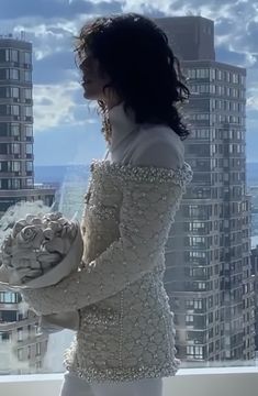 a woman standing on top of a building holding a bouquet of flowers in her hands