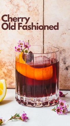 an old fashioned cocktail is garnished with fresh flowers and lemons on the table