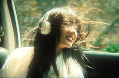 a woman sitting in the back seat of a car with headphones on her ears