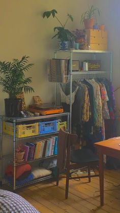 a room with a metal shelf filled with books and other items next to a bed