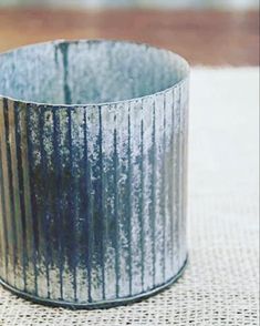 a metal cup sitting on top of a burlap tablecloth covered placemat