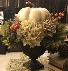 a vase filled with white pumpkins and flowers on top of a marble countertop