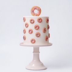 a white cake with pink frosting and donuts on it