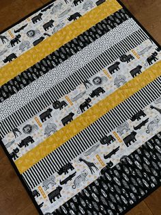 a black and white quilt with yellow strips on the bottom that has elephants all over it