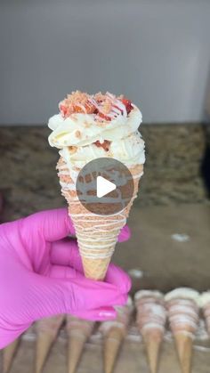 someone holding up an ice cream cone with toppings on it in front of other cones