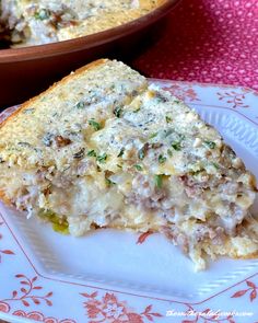 a slice of quiche on a plate with another dish in the back ground behind it