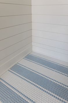 a bathroom with white walls and blue patterned flooring on the floor, along with a toilet