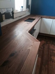 an empty kitchen with blue walls and wood flooring on the countertop, in front of a window