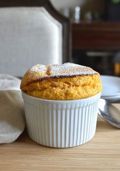 a cupcake with powdered sugar on top sits on a table next to a plate