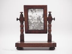 an old fashioned wooden mirror sitting on top of a stand