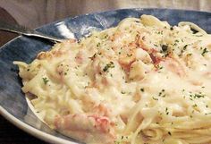 a plate of pasta with shrimp and cheese on it is sitting on a wooden table