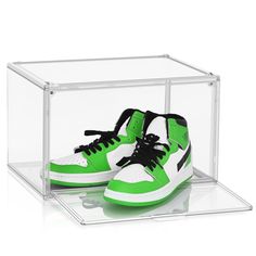 a pair of green and white sneakers in a clear box with black laces on the bottom