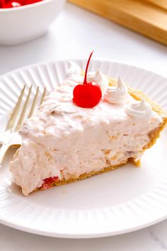 a white plate topped with a piece of cake covered in whipped cream and cherries