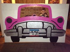 a pink car painted on the side of a white wall with a child sitting in it