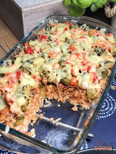 a casserole dish filled with meat, vegetables and cheese on top of rice