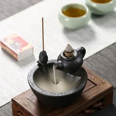 a bowl with two birds on it sitting on a table next to some tea cups