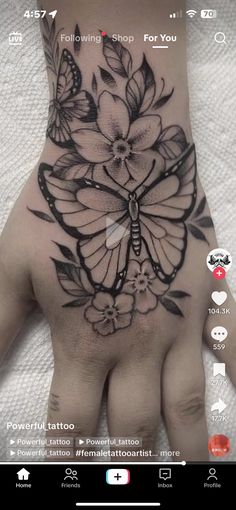 a person's hand with a butterfly tattoo on it and flowers in the middle