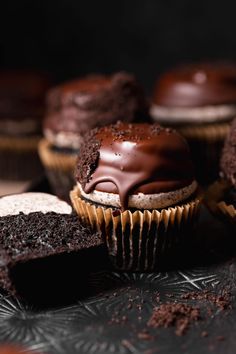 chocolate cupcakes with frosting and sprinkles on a black surface