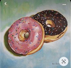 two donuts with chocolate and sprinkles are on a blue surface,