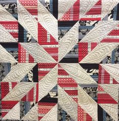 a red and black quilt with white strips on the center is featured in this image