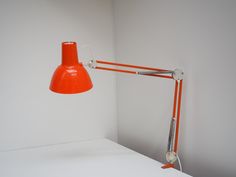 an orange table lamp sitting on top of a white counter next to a light fixture