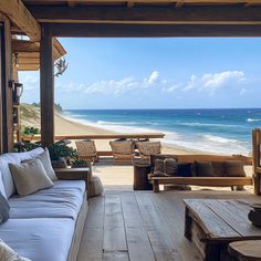 an outdoor living area with couches and tables on the deck next to the ocean