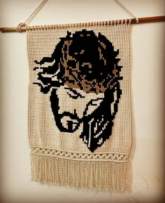 a woven wall hanging with an image of jesus in black and gold on it's side