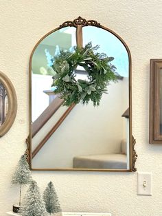 a mirror hanging on the wall next to a christmas wreath