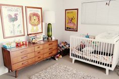 a baby's room with a crib, dresser and pictures on the wall