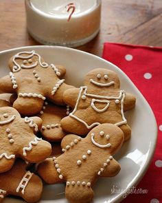 a white plate topped with cut out gingerbread cookies next to a glass of milk