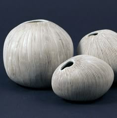 three white vases sitting next to each other on a blue surface with black background