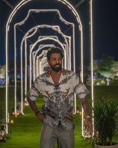 a man standing in the middle of an archway with lights all around him and his hands on his hips