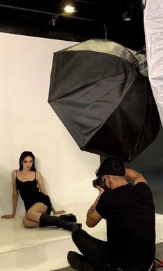 a woman is sitting on the floor with an umbrella in front of her, while a photographer takes pictures